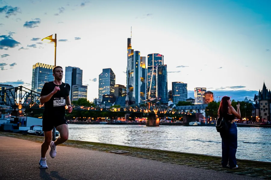 Läufer am Mainufer vor der Frankfurter Skyline in der Dämmerung
